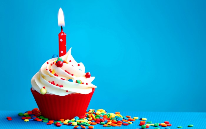 Birthday cupcake with a lit candle and sprinkles