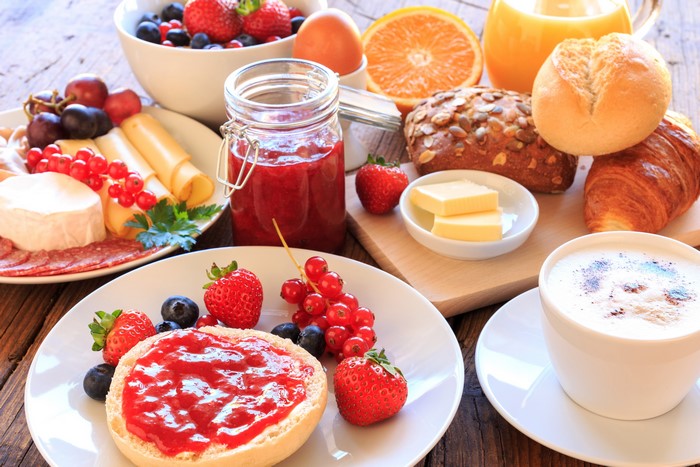 Breakfast with jam, cheese, fruit, and coffee