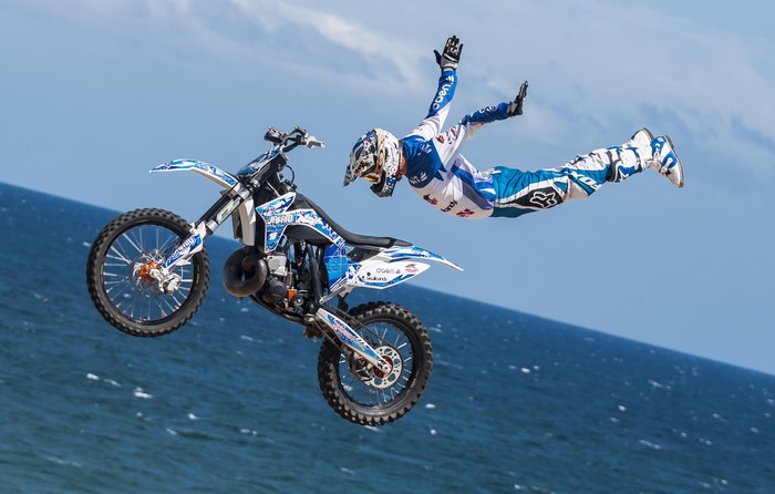 Motocross rider performing a stunt jump over the ocean