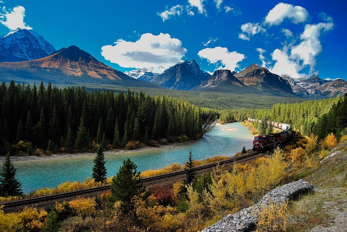 Train traveling through a mountain valley in autumn