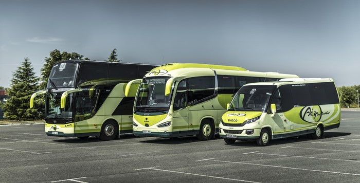 Three buses and a minibus parked in a lot