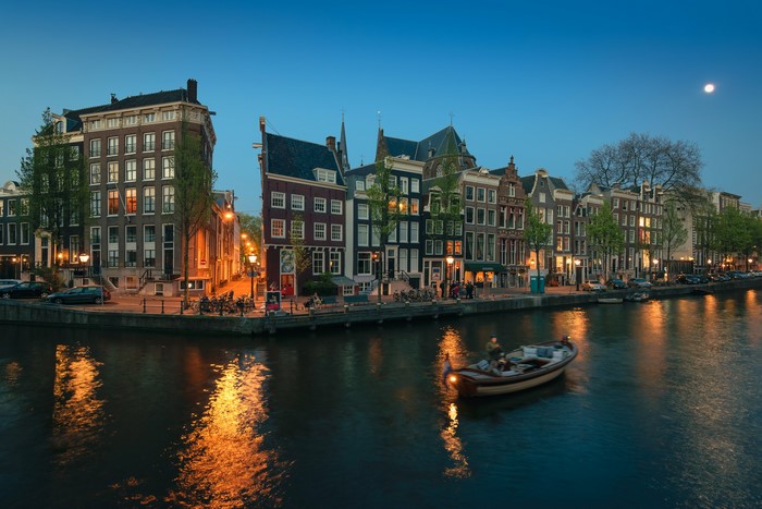 Amsterdam canal at dusk with a boat and moon