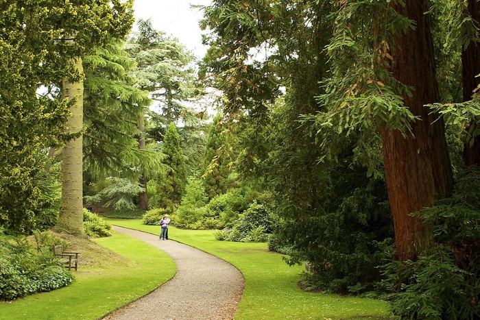 A couple walks on a path in Biddulph Grange Garden, United Kingdom