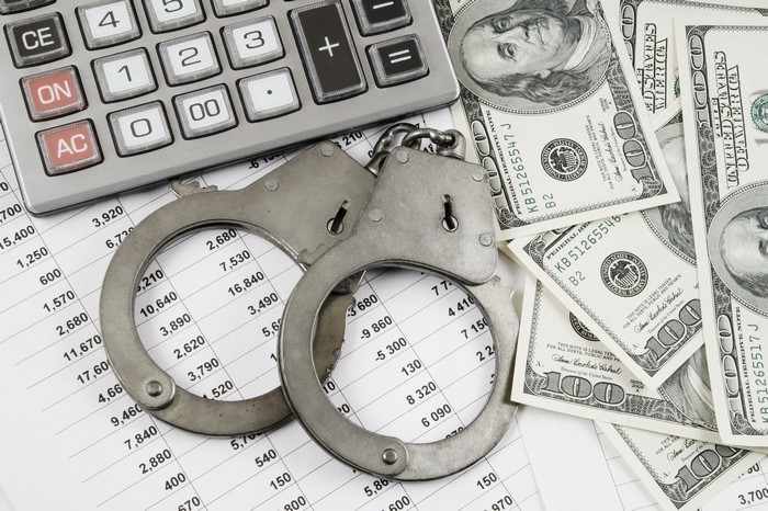 Handcuffs, Calculator, and US Dollar Bills on Financial Documents