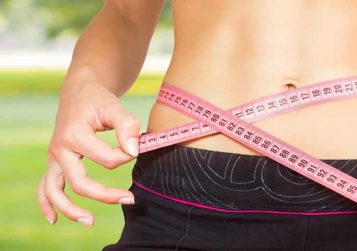 Woman measuring waist with tape measure