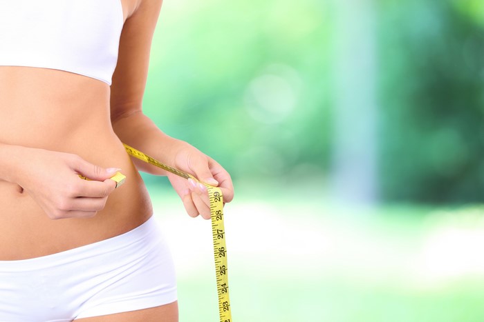 Woman measuring her waist with a tape measure