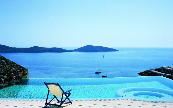 Infinity pool overlooking the sea with sailboats