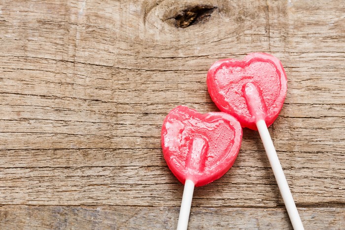 Two pink heart lollipops on wood