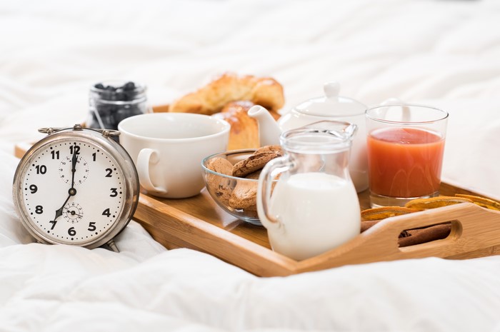 Breakfast tray with clock, croissants, juice, and milk