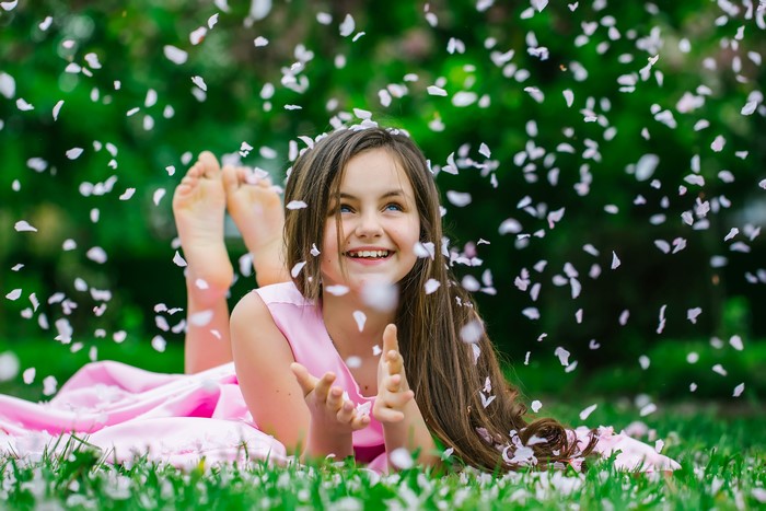 Girl in pink dress with petals falling