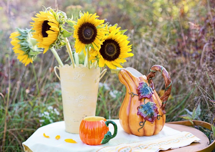 Sunflowers in a vase with a pumpkin jug and mug