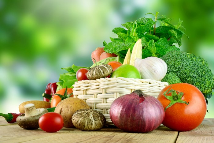 Vegetables in a wicker basket with a green background