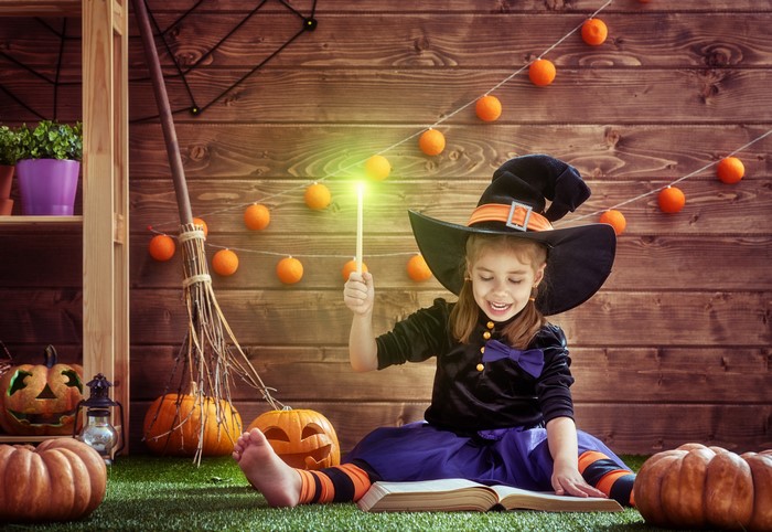 Girl in Witch Costume with Magic Wand and Book