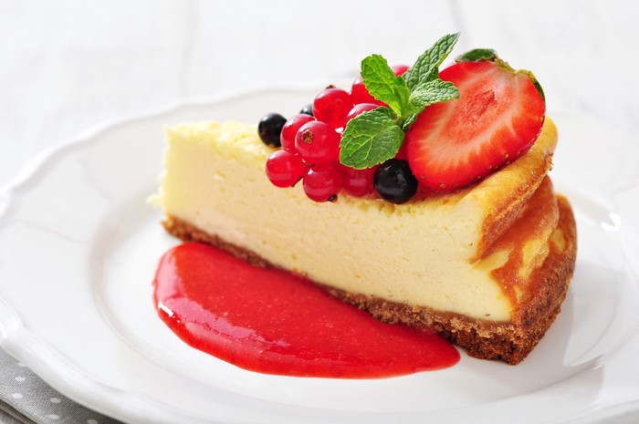 Slice of cheesecake with berries and strawberry sauce