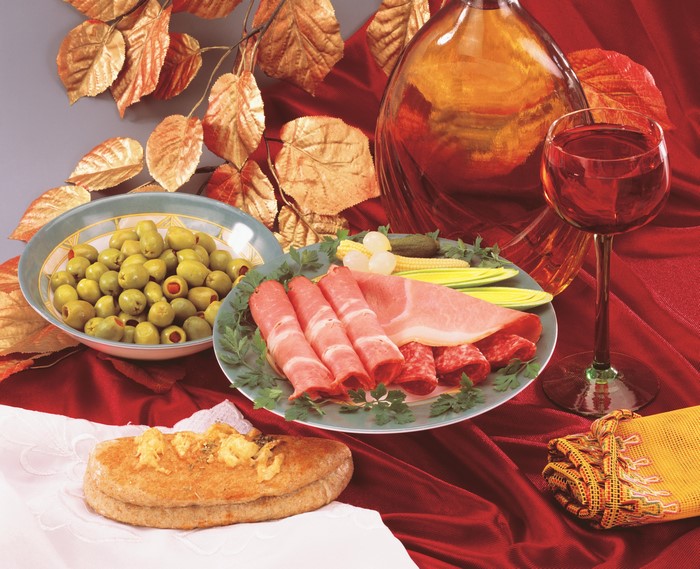 Appetizer spread with olives, cured meats, bread, and wine