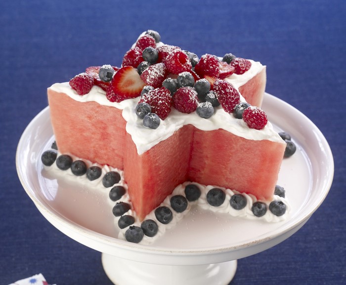 Star-shaped watermelon cake with berries and whipped cream