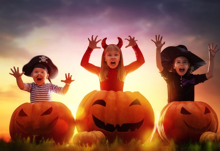 Three children in Halloween costumes with pumpkins