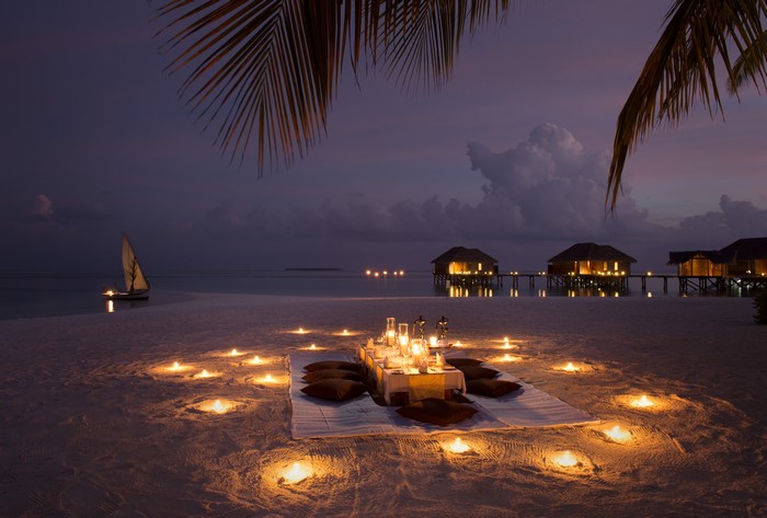 Romantic beach dinner with candles and overwater bungalows