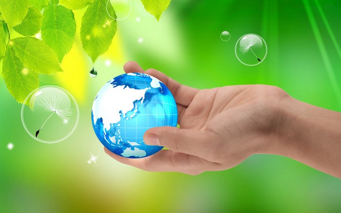 Hand holding a globe with green leaves and bubbles