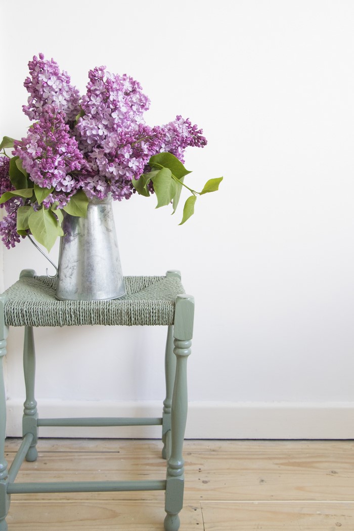 Bouquet of lilacs in a metal jug on a stool