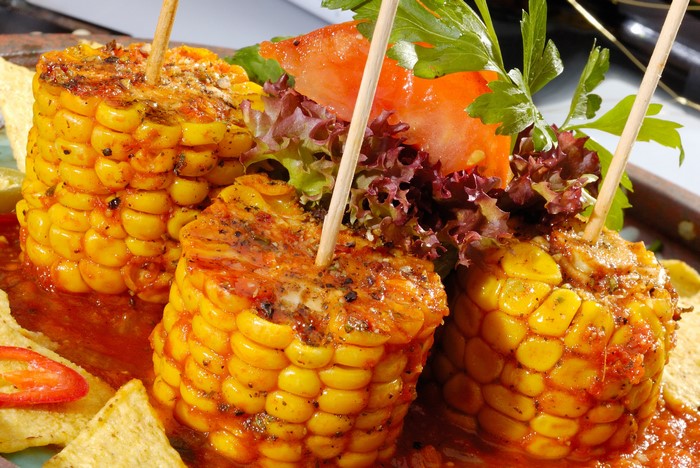 Corn on the cob with sauce and chips