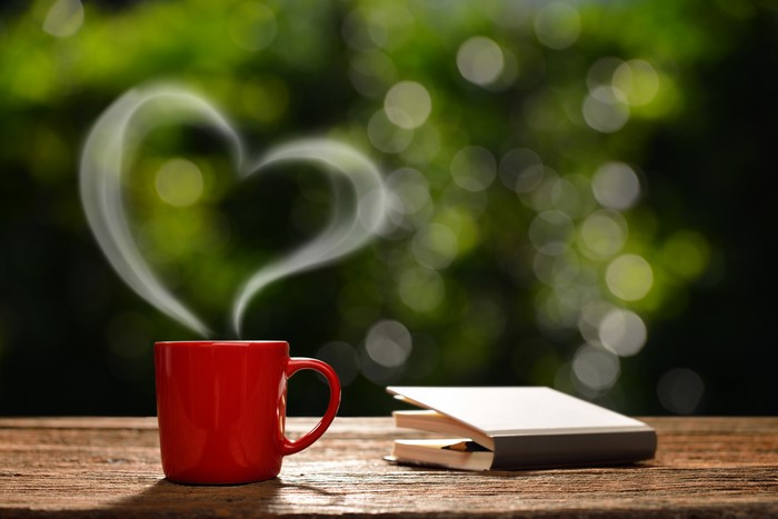 Red mug with heart-shaped steam and book
