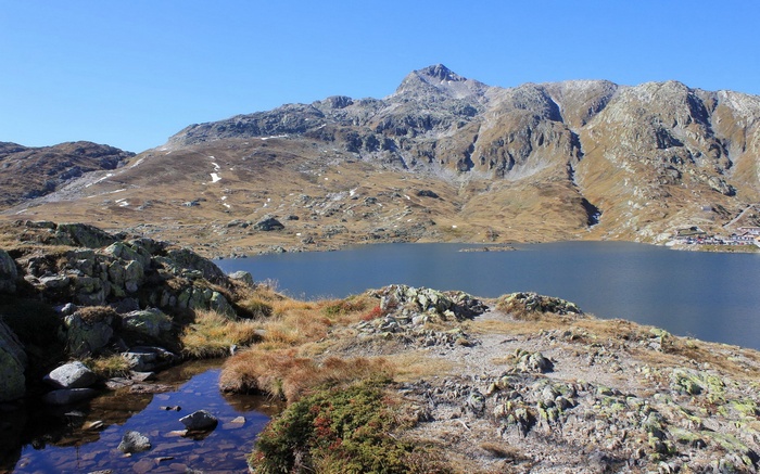 Mountain lake with rocky shore and distant buildings