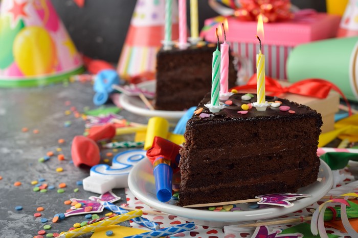 Chocolate cake slices with birthday candles and party decorations