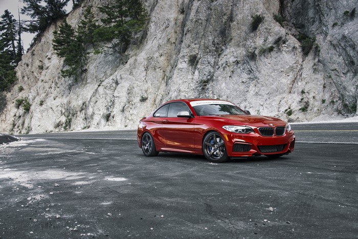 Red BMW M235i F22 on a mountain road
