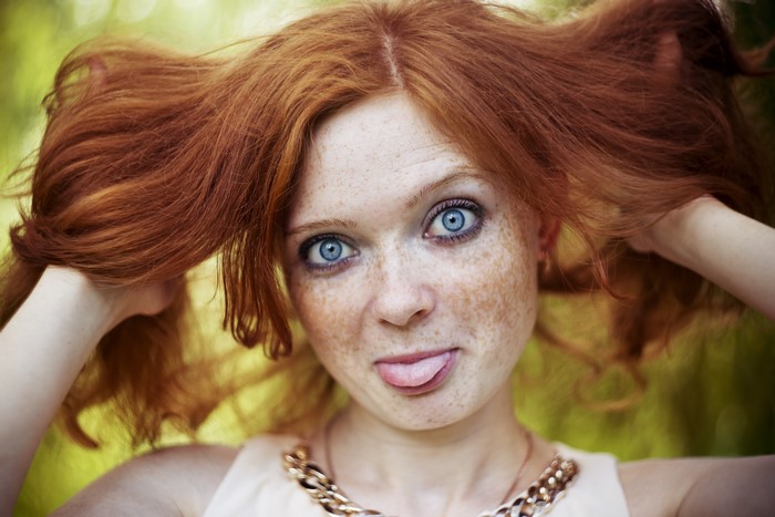 Redhead girl with blue eyes sticking out tongue