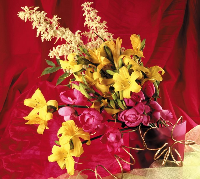Bouquet of yellow lilies and pink peonies in a red vase