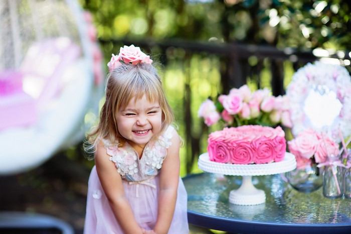 Little girl with pink cake at birthday party