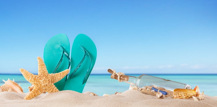 Starfish and Flip-flops on a Sandy Beach with Message in a Bottle
