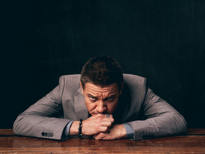 Jeremy Renner in a suit looking down