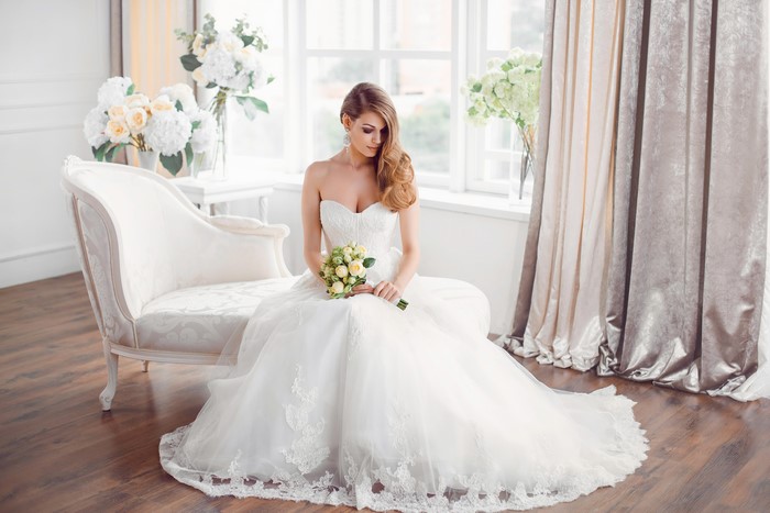 Bride in a white dress sitting with a bouquet