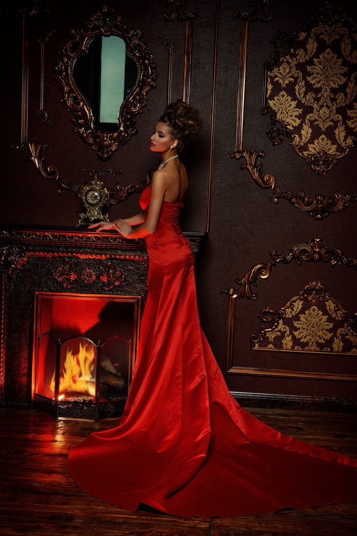 Woman in red dress by fireplace