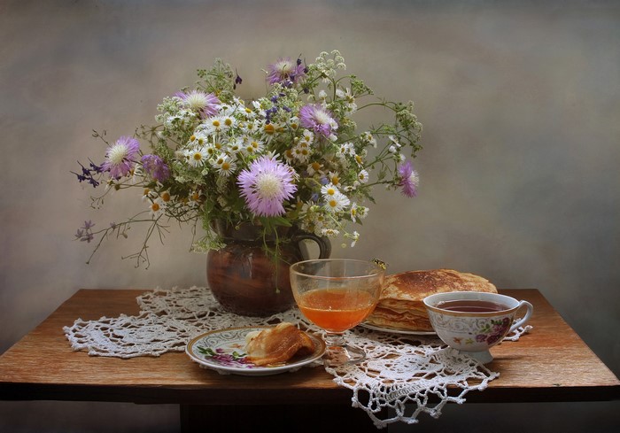 Still-life with wildflowers, pancakes, tea, and honey