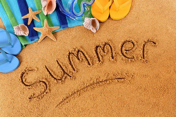 Summer written in sand with beach accessories
