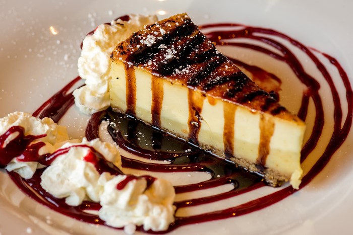 Cheesecake slice with whipped cream and berry sauce