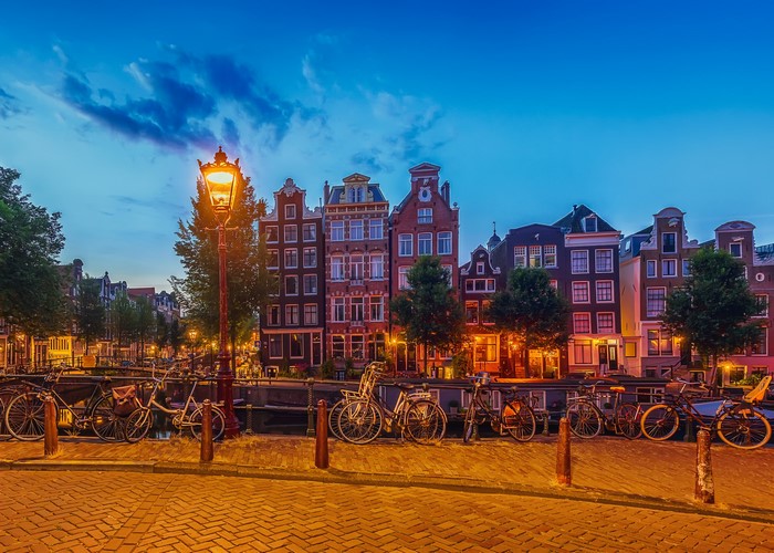 Amsterdam canal with houses and bicycles at dusk
