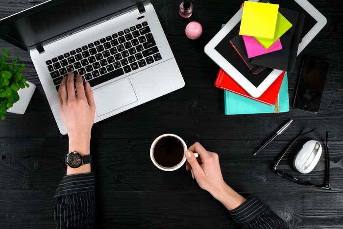 Overhead view of a person working on a laptop with coffee