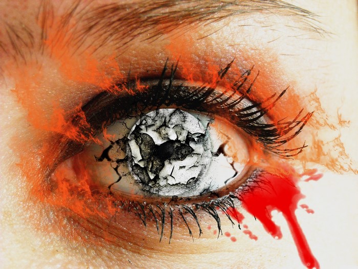 Close-up of a cracked eye with blood and orange makeup