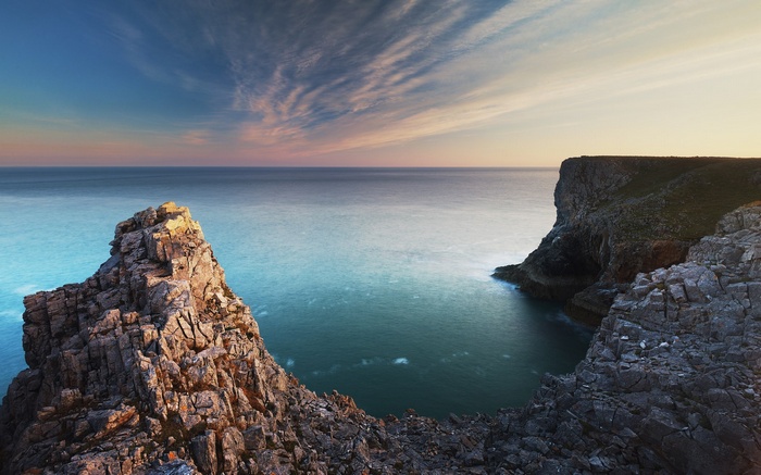 Rocky coastline at sunset with ocean and sky