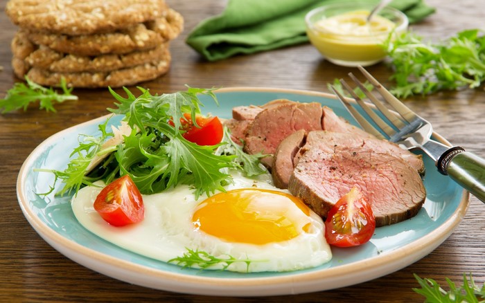 Fried egg with sliced meat and salad