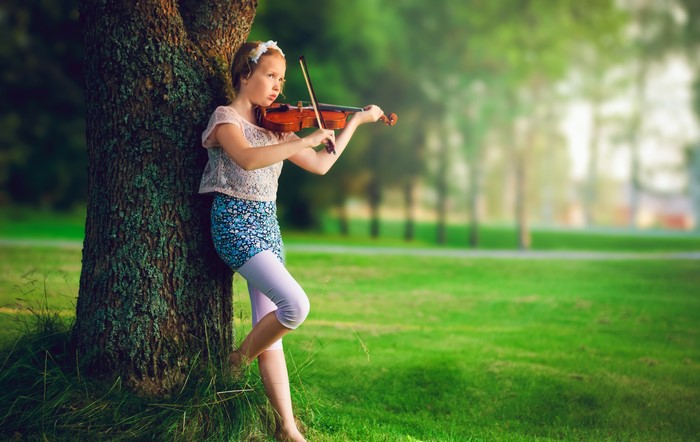 Girl playing violin by a tree