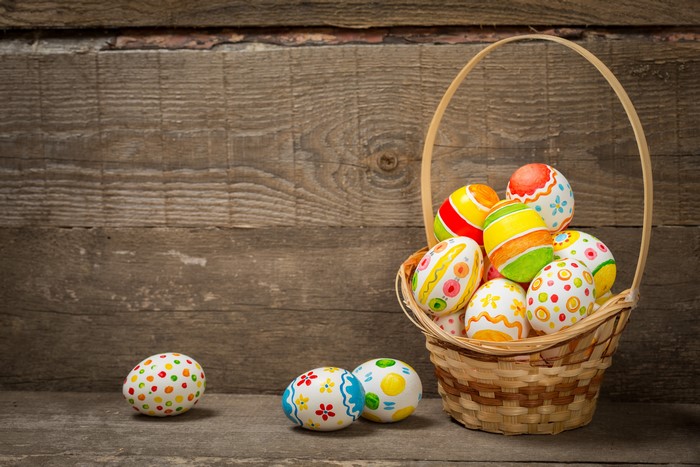 Easter eggs in a wicker basket on a wooden background