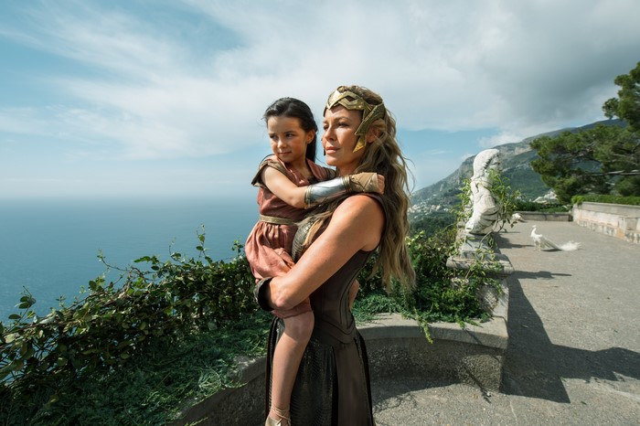 Wonder Woman holding a young girl on Themyscira