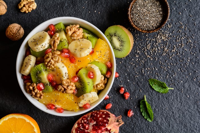 Fruit salad with kiwi, banana, orange, pomegranate, walnuts, and chia seeds