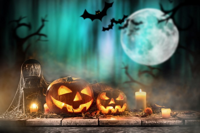 Halloween pumpkins and bats under a full moon