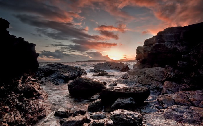 Rocky coastline at sunset with colorful clouds